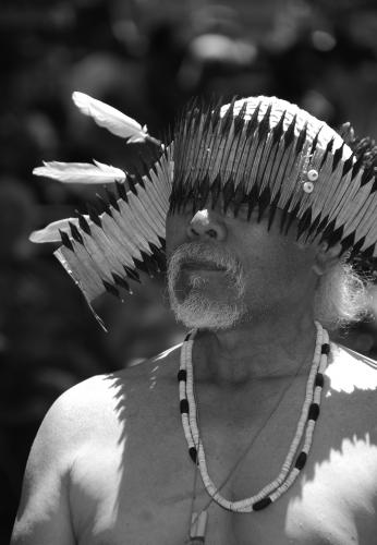 A black and white image of a man wearing regalia, photographed form the chest up.