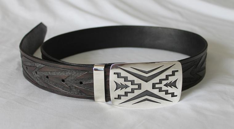 A carved leather belt and sterling silver belt buckle with chevron designs.