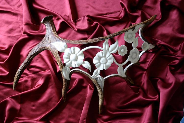 An antler carved so that it looks like it is decorated with white flowers