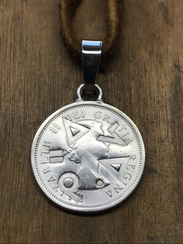 A silver coin stamped with Cree words that translate to “Speak Cree.”