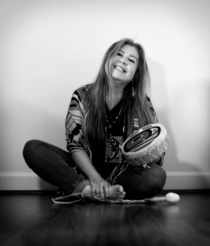 A black and white portrait of the poet Donna Beaver holding a hand drum