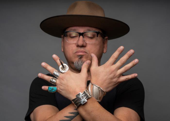 Artist Erik Lee holding up his hands, showing silver rings and bracelets he created