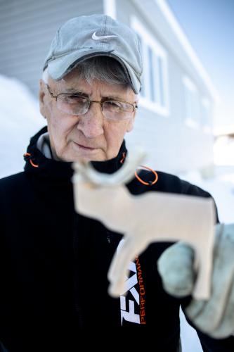 A man looks at a caribou carving he is holding