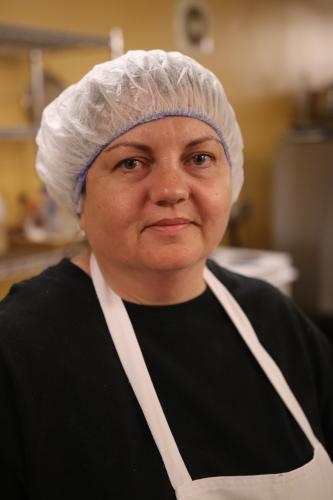 A portrait of a woman cook in her apron and hair net