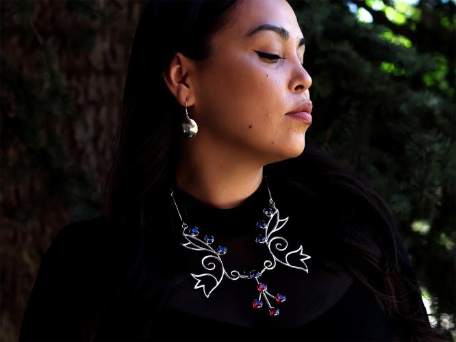 A woman models a necklace with a flower design and pair of earrings