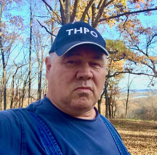 Portrait of Lance Foster wearing a hat that has the initials THPO, for tribal historic preservation officer