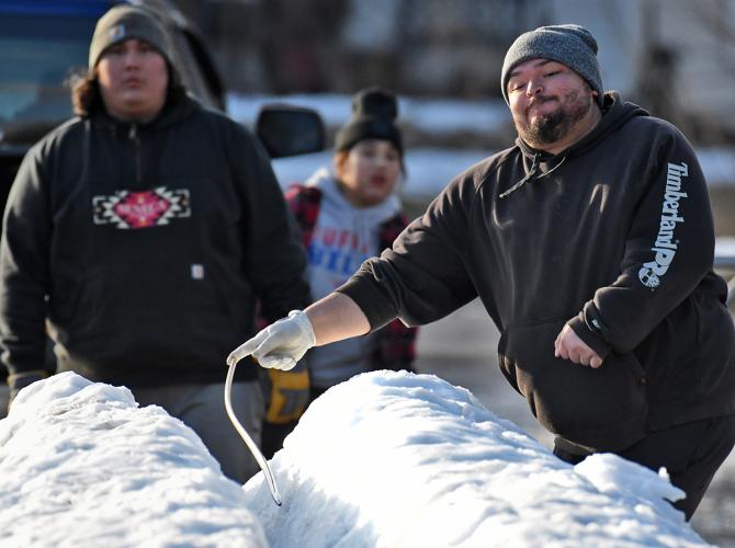 A man throws a carved snake down the snowy track