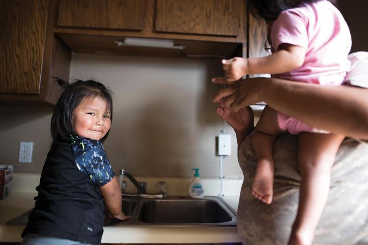 A child smiles as water runs from a tap