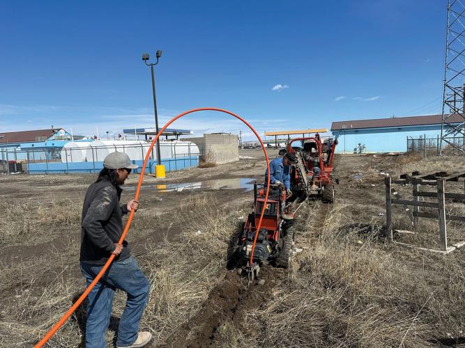 Two men use machinery to prepare the ground for fiber optic cable installation
