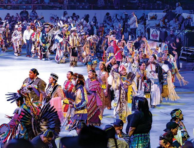 Powwow participants in regalia form a spiral during the Grand Entry