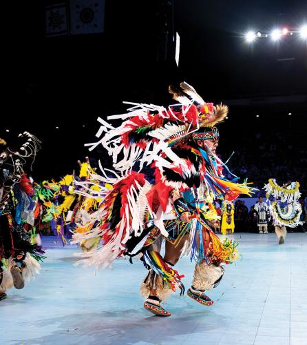 A male dancer in a colorful outfit decorated with ribbons