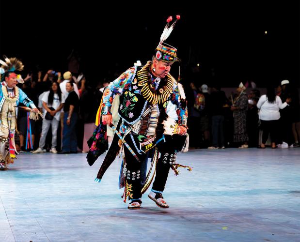 A male dancer wearing an embroidered outfit and a breastplate