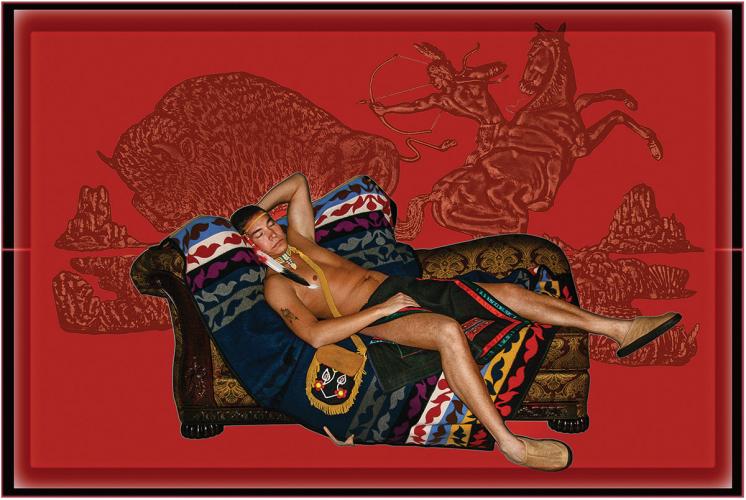 Inkjet print showing a man asleep and reclined on a sofa covered in a blanket, against a red background.