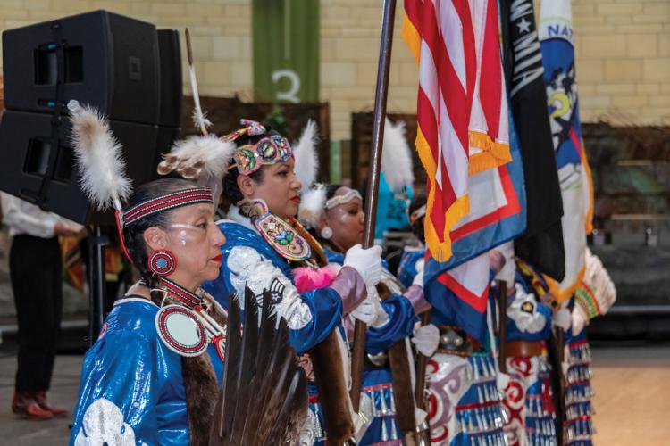 A row of six Native women veterans in regalia holding flags 