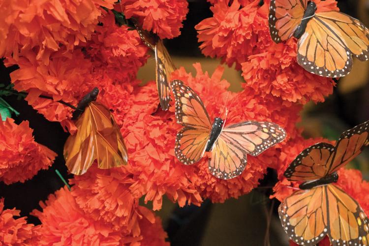 Monarch butterfly decorations placed among paper marigold decorations