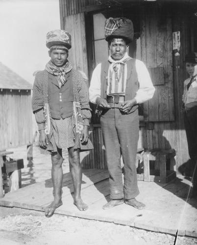 Black and white photograph of two Seminole men standing outside a building