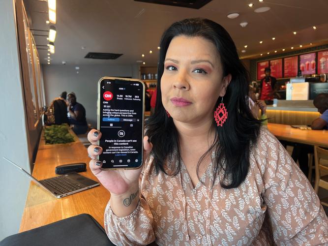 Journalist Francine Compton holds up a phone with a message that her access to CNN news feed is blocked in a cafe