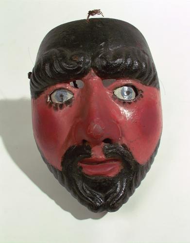 A carved mask depicting a red-brown face with black hair and beard