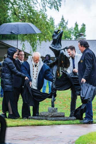 A group of people unveil a restored statue