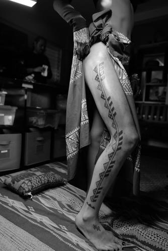 A person displaying the traditional Hawaiian tattoo that stretches from their hip to their ankle