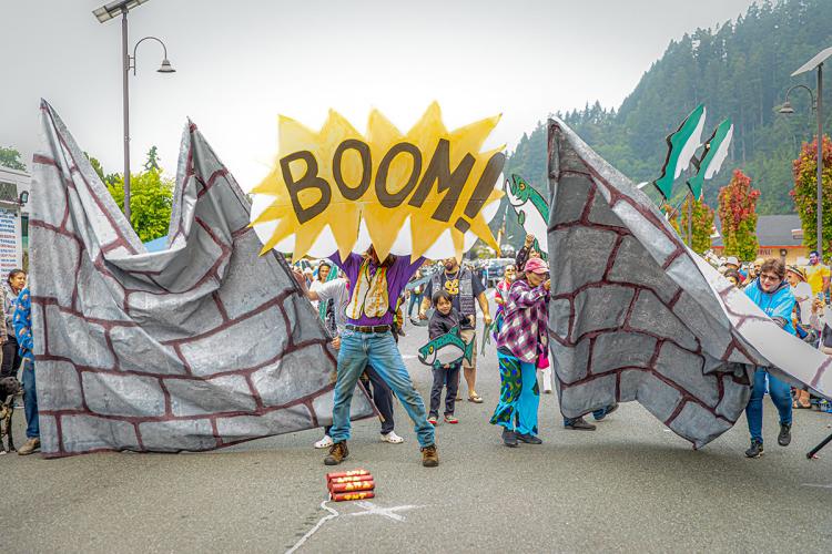 People hold props and a sign reading "Boom" during a pantomime of a dam explosion