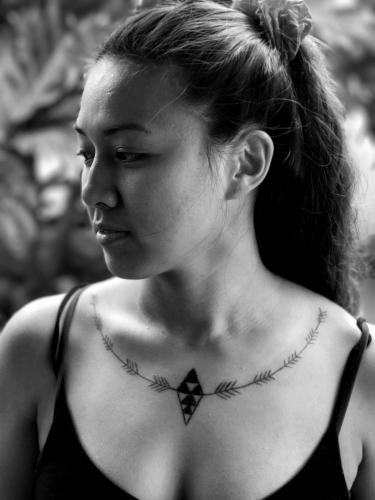 A traditional Hawaiian tattoo adorns a woman's collarbone