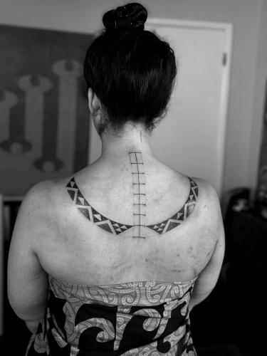 A woman's back adorned with a traditional Hawaiian tattoo