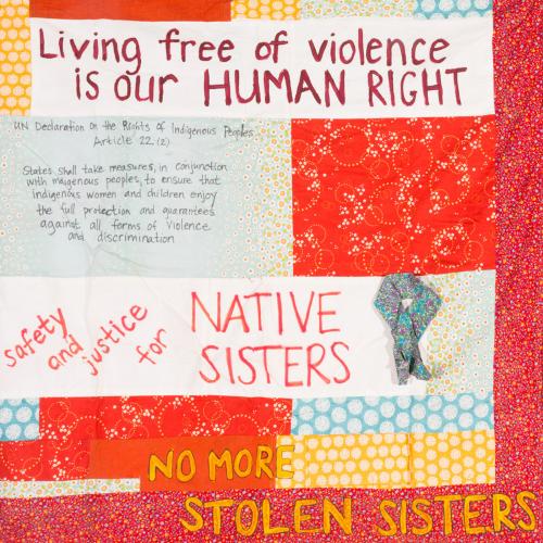 A closeup of a quilt piece with text, including the words "No More Stolen Sisters" 