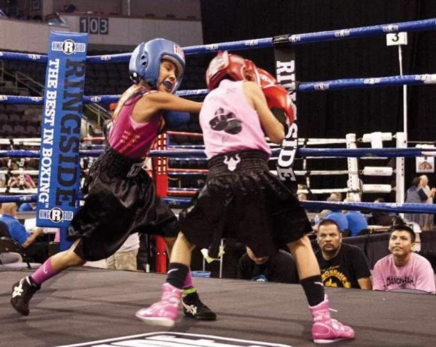 Two young girls compete in a boxing ring
