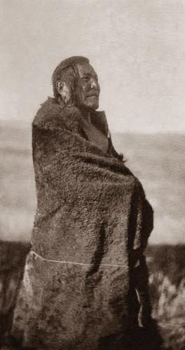 A historic photograph of a man standing with a blanket wrapped around him