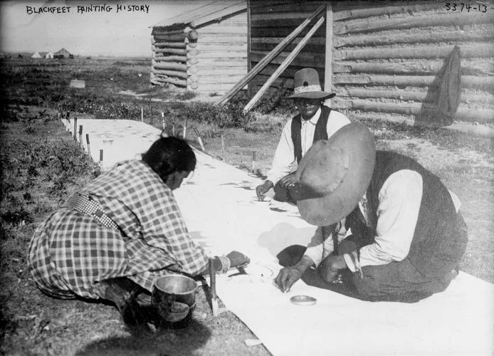 Black and white archival photo of three artists painting on a large length of cloth