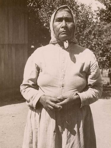 A sepia portrait of a Lucy Young standing with hands clasped