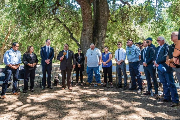 A group of Indigenous Californians standing in a circle with the California governor under trees