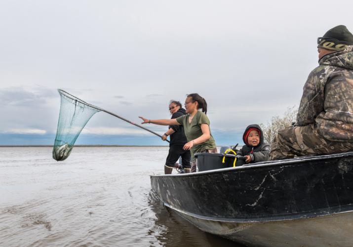 A group of people on a boat fishing with a dipnet on the Kuskowim River.