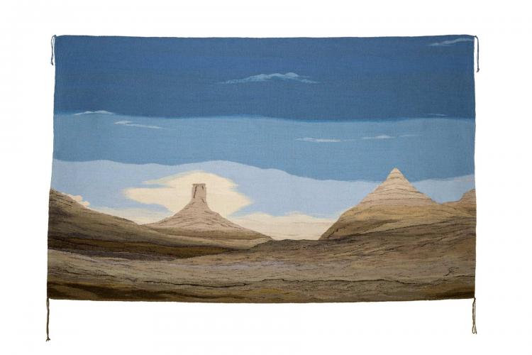 Woven wool tapestry depicting desert and mesa landscape against a cloudy blue and white sky.