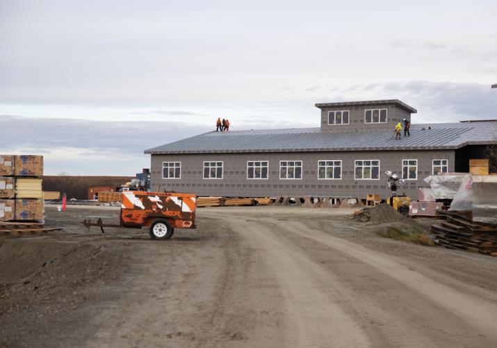 Workers installing roofing on a new school building.