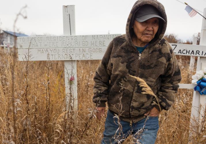 Person standing near a sign marking a mass grave.