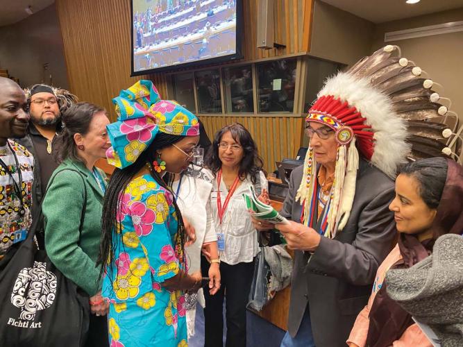 Chief Wilton Littlechild, wearing a headdress, accepts a peacemaking docume