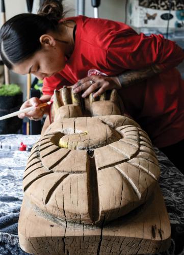 Artist Nakesha Edwards working on a wooden totem pole.