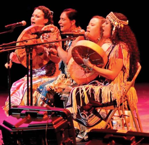 Drum and vocal group Ulali perfoms on stage in traditional indigenous dress.