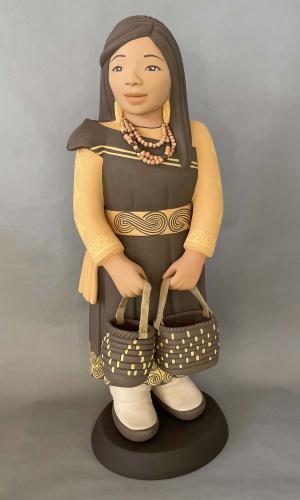 Clay sculpture of girl wearing beaded necklace and dress carrying two woven baskets