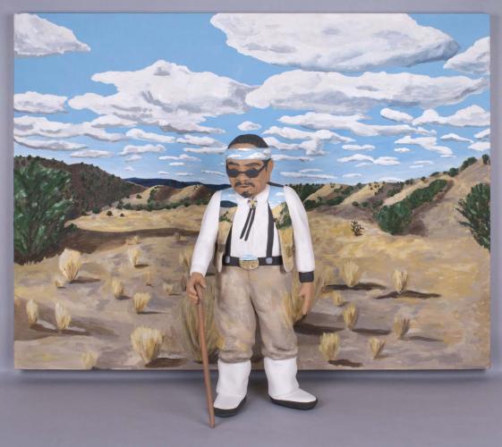 Clay sculpture of man in vest and headband in front of painting of landscape