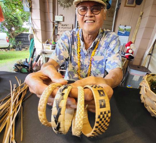 Man smiles as he displays woven bracelets