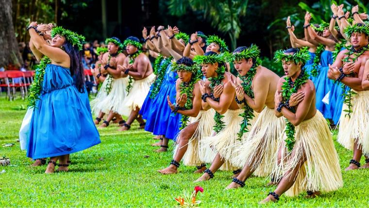 Group of people performing Hula in traditional Hawaiian dress
