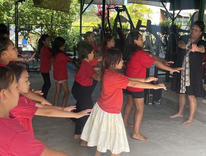 Children practice hula dance with instructor