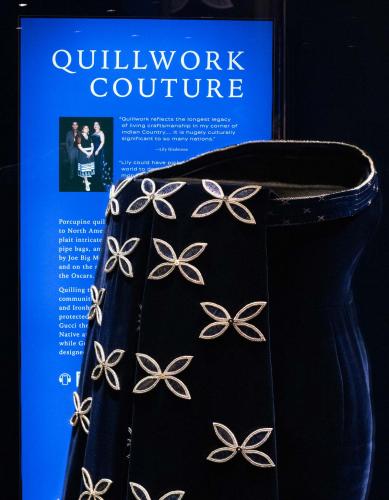 Detail of dress on display beside a museum exhibit panel