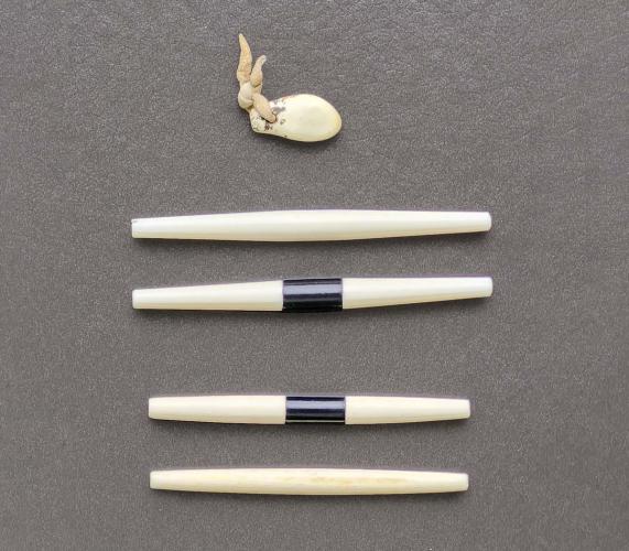 Small handheld game pieces made of bone or plastic resemble small sticks.