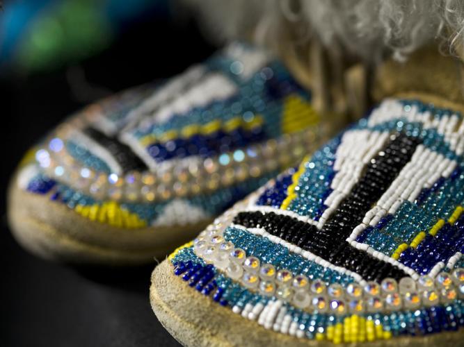Blue, purple, yellow, and white beads adorn leather footwear.
