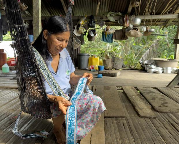 Weaver displays woven belts depicting flora and fauna.