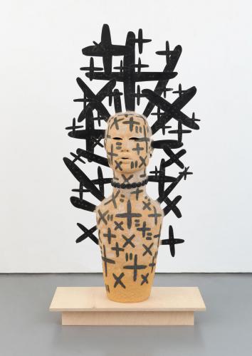 Sculpture of human form surrounded by black plus signs and x's.